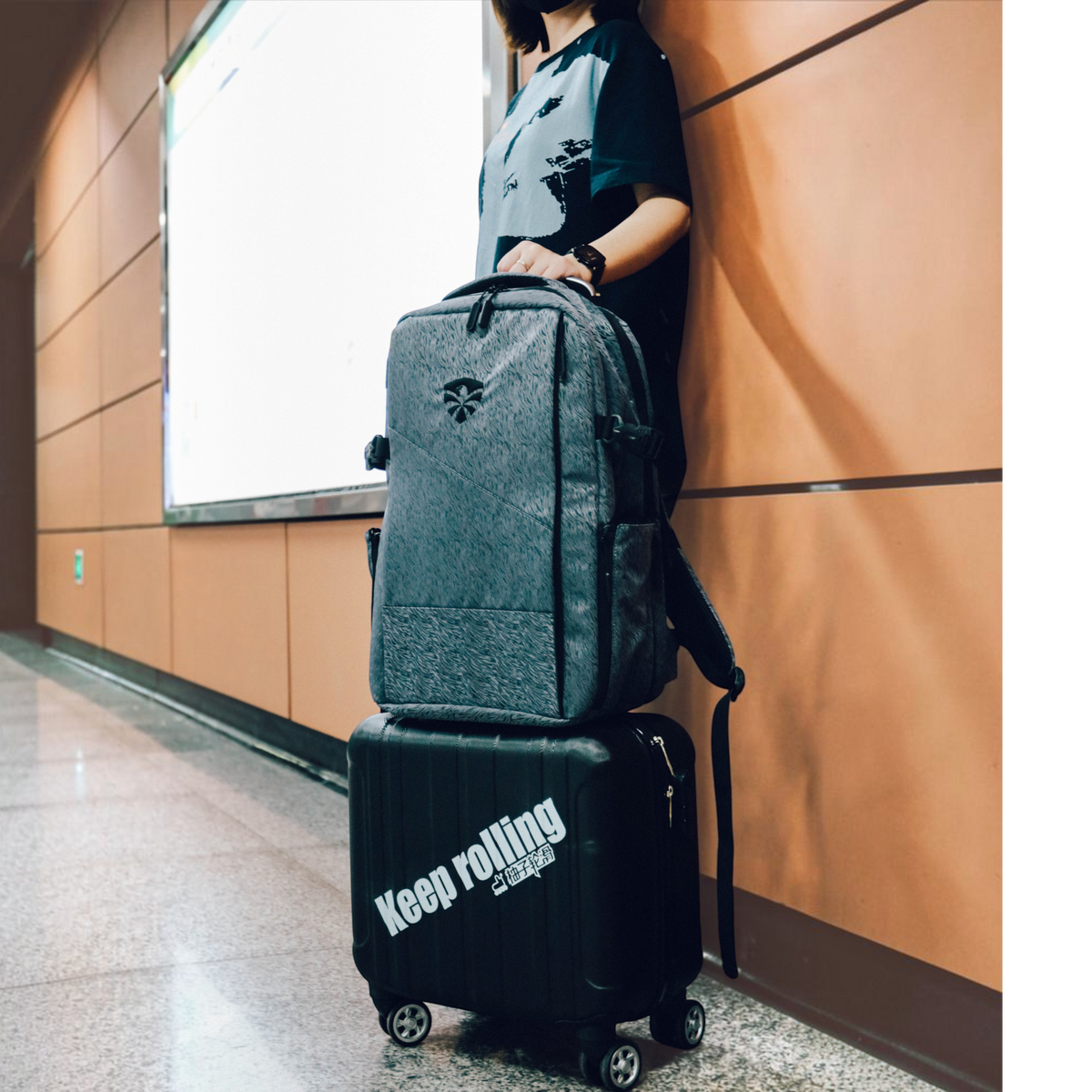 Mochila KonRoller FlyingEagle Movement cinza tamanho G apoiada sobre mala preta em ambiente urbano