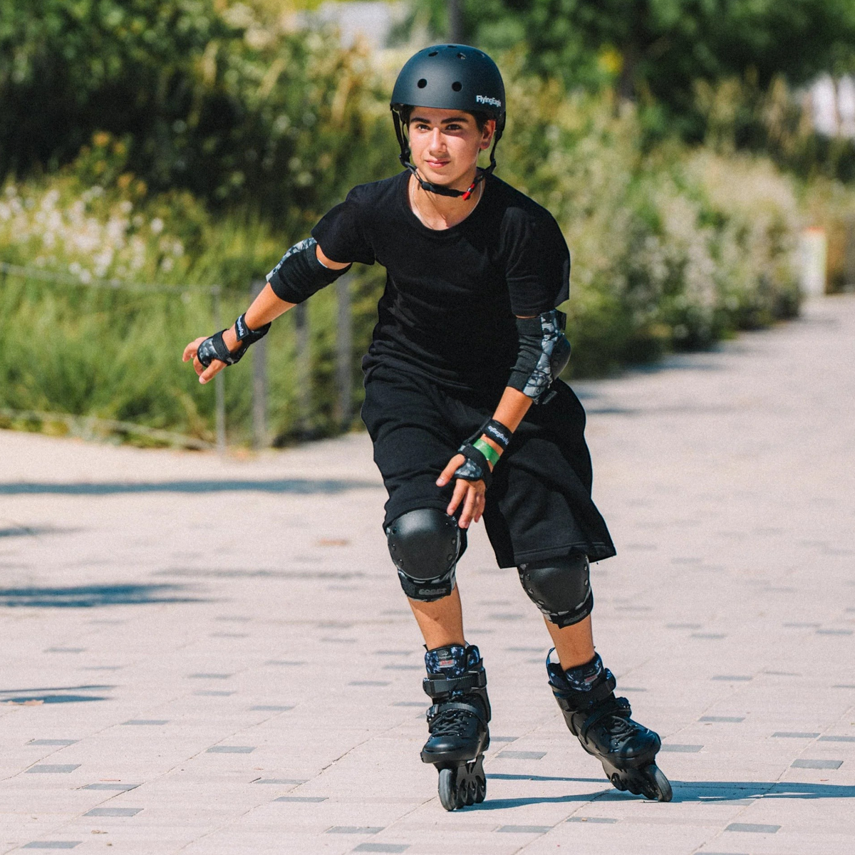 Pessoa patinando em parque usando capacete preto FlyingEagle Urban da KonRoller com proteção de joelhos e cotovelos