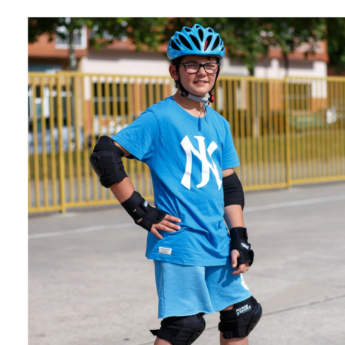 Menino usando capacete azul FlyingEagle Rapido JR, joelheiras e cotoveleiras KonRoller para patinação ao ar livre.