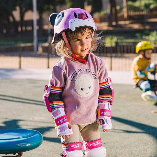 Criança usando capacete infantil KonRoller FlyingEagle KT rosa com estampa de leopardo e kit de proteção completo