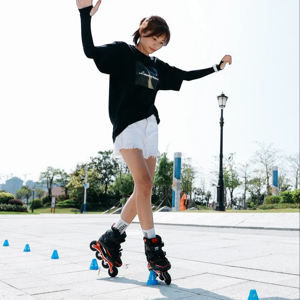 Patinadora KonRoller praticando freestyle slalom com cones azuis FlyingEagle em uma praça ao ar livre