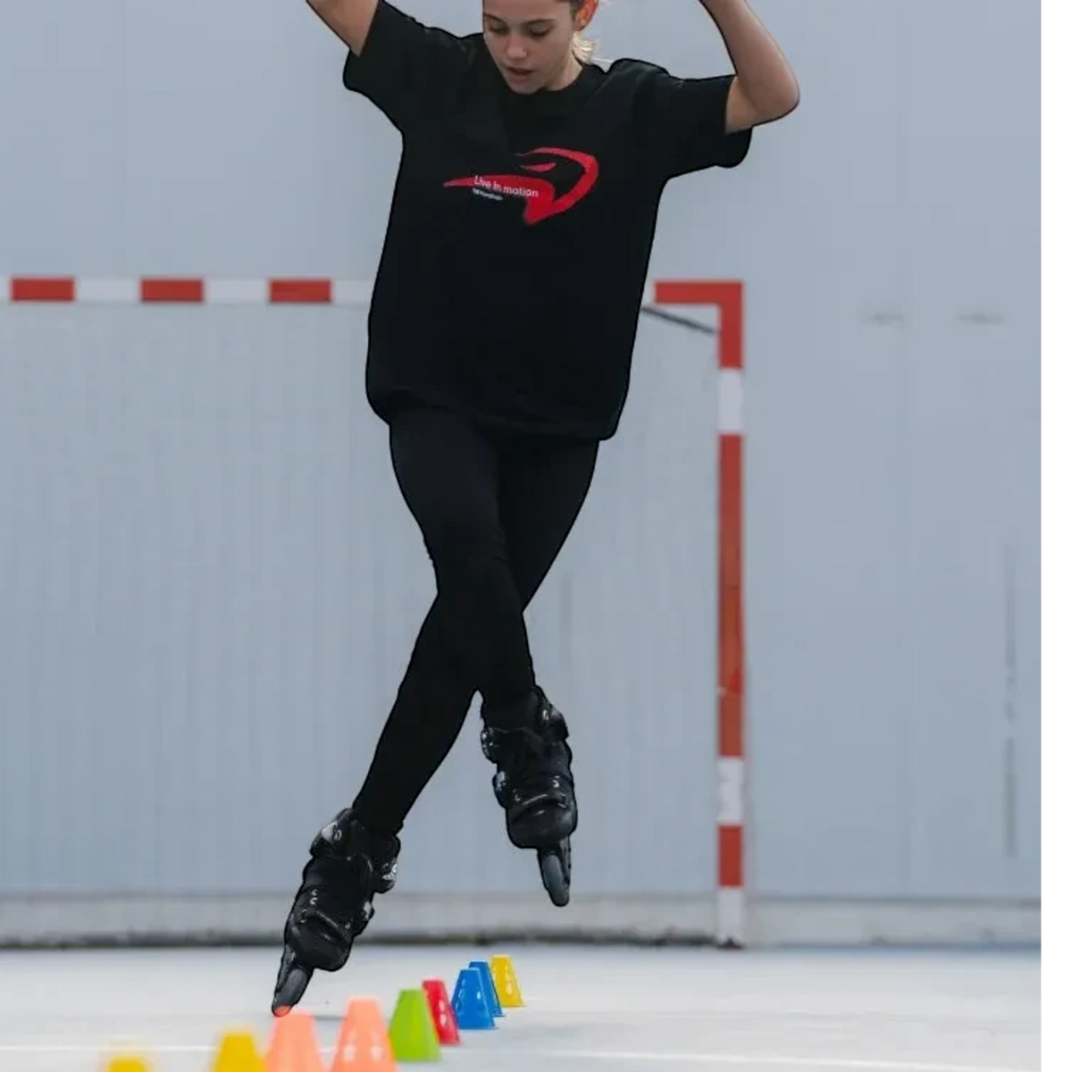 Patinadora KonRoller praticando freestyle slalom com cones coloridos FlyingEagle em uma quadra esportiva
